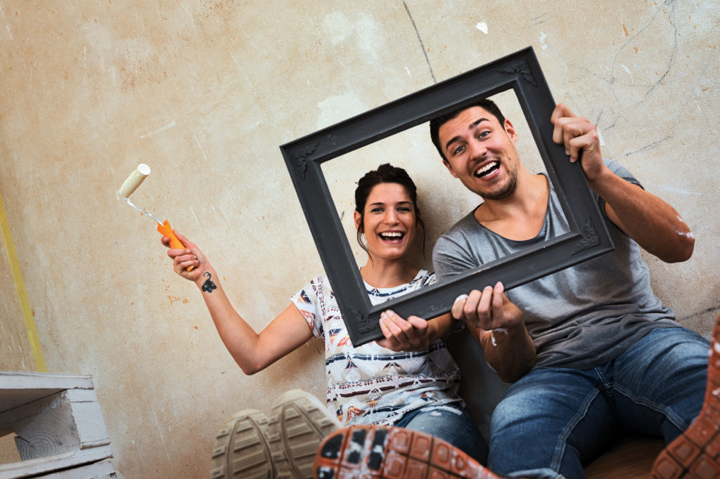couple redecorating home and holding picture frame