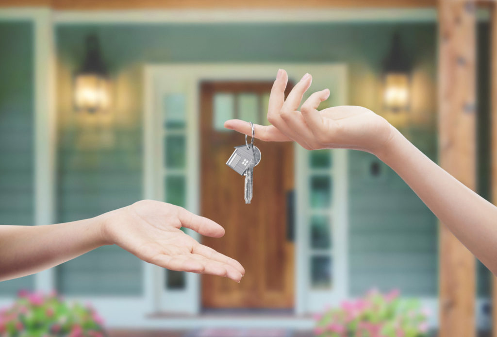 Person Handing the Key to a House to Another Person